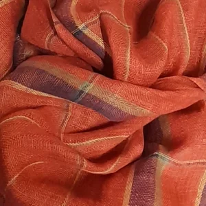 Close-up of a handwoven linen scarf in madder red, showing fine texture and subtle highlight threads.